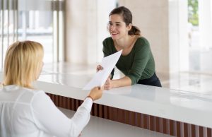 Front Desk Lady Offering Tourist To Fill Out Documents