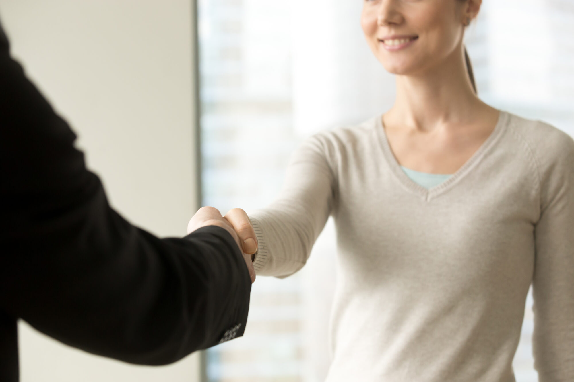 Smiling Businesswoman Shaking Businessman Hand In Office, Close
