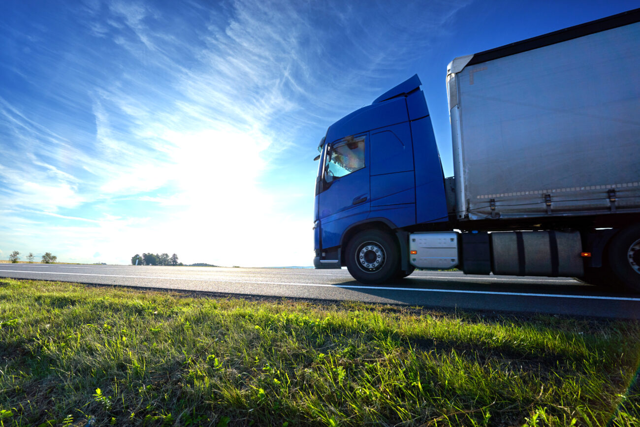 Blue Truck Driving On The Asphalt Road On A Horizon Against The