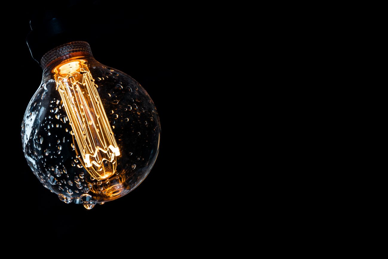 Warm Colored And Glowing Bulb With Water Drops On A Dark Background.