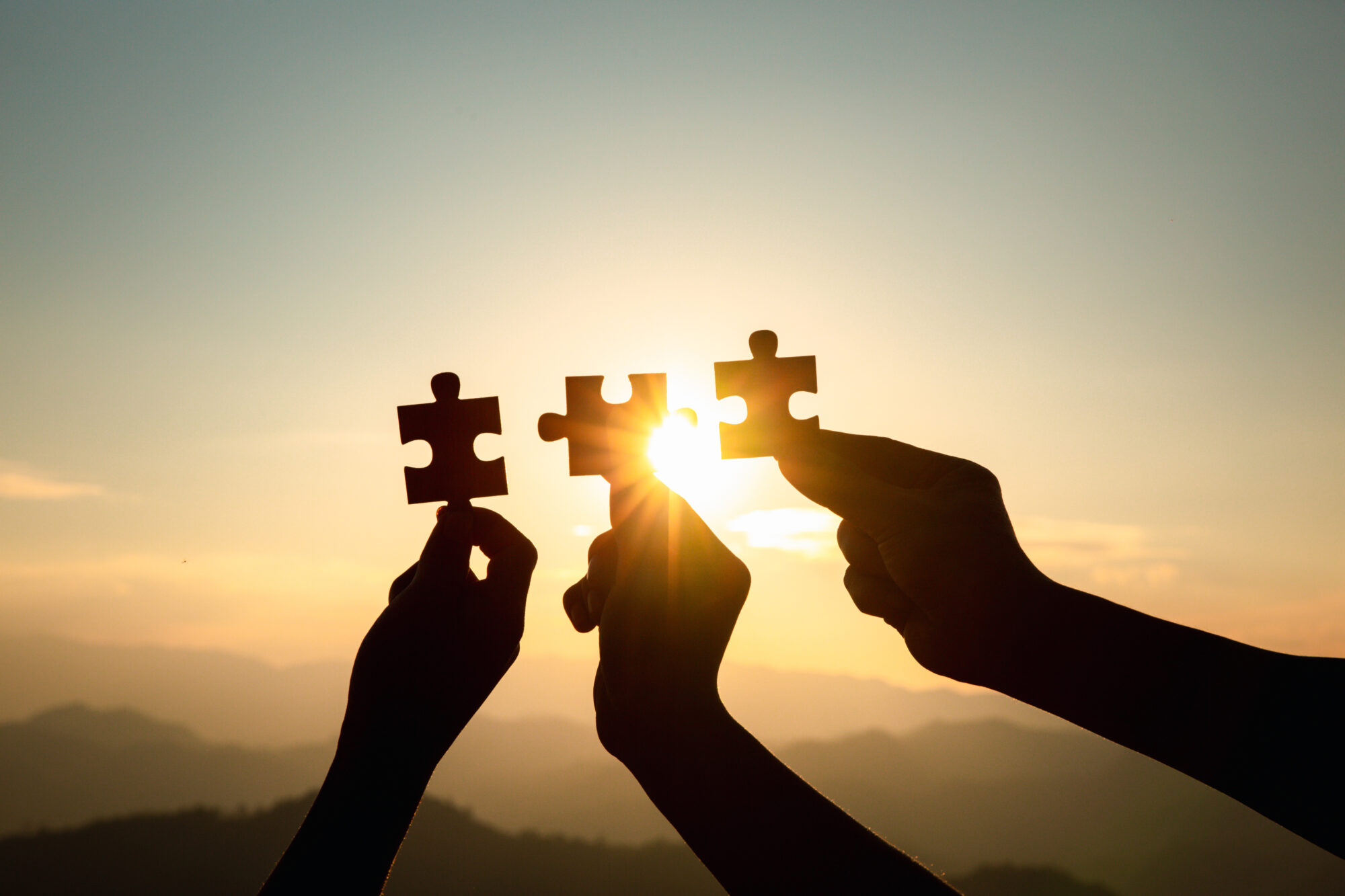 Silhouette Of Hand Holding Jigsaw With Sunrise Background. . Sym