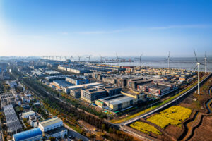 Large Modern Industrial Park With Wind Turbines Along The Coast Under Bright Sunlight.