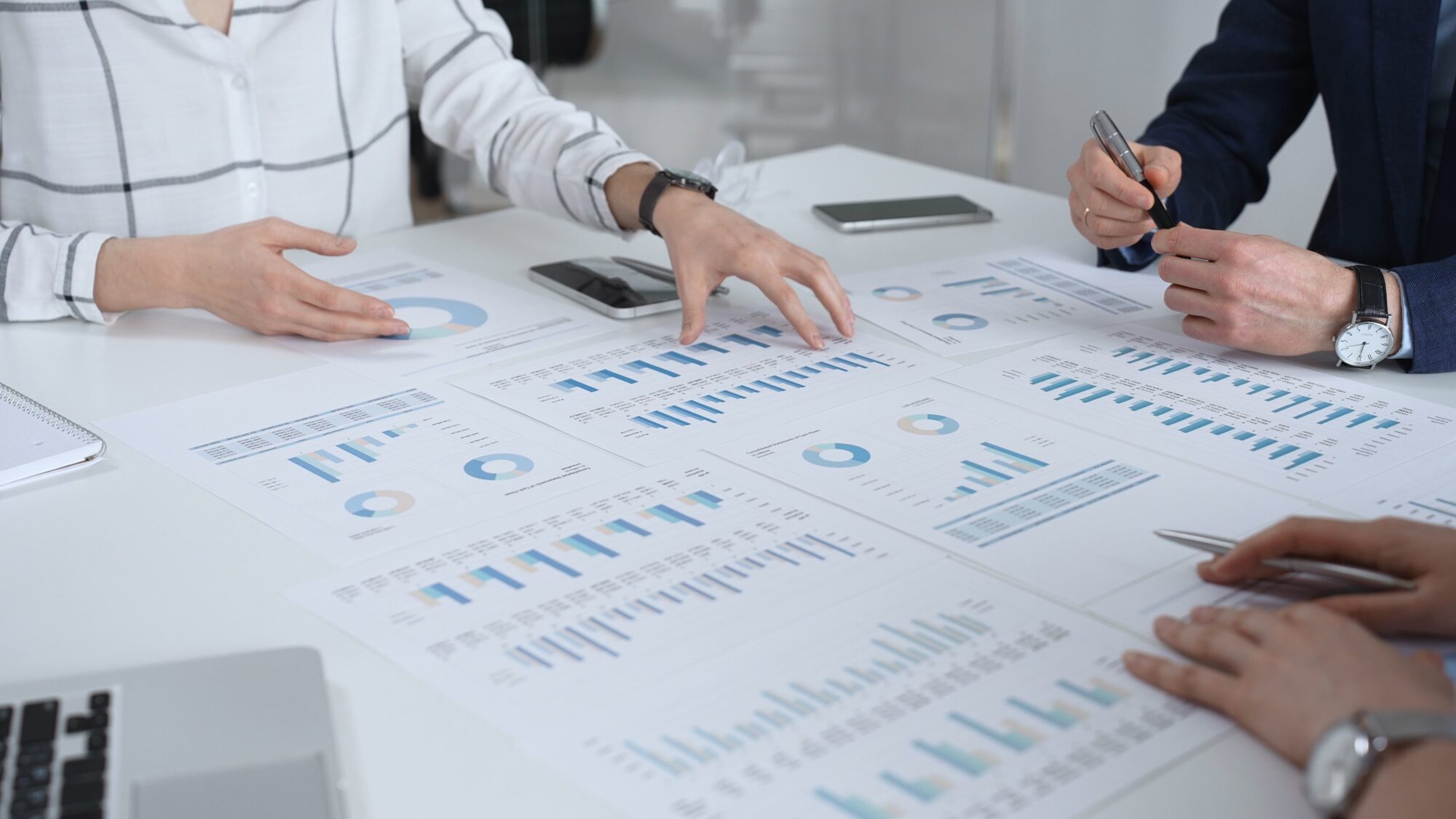 Business Team In A Conference Room Reviewing Financial Reports, Charts And Graphs Across The Table, Collaborating On Strategy, Investment Planning And Growth Initiatives