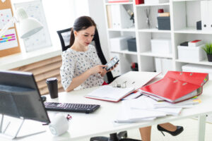 A Young Girl Sitting In The Office At The Table, Said On The Calculator And Working With Documents.