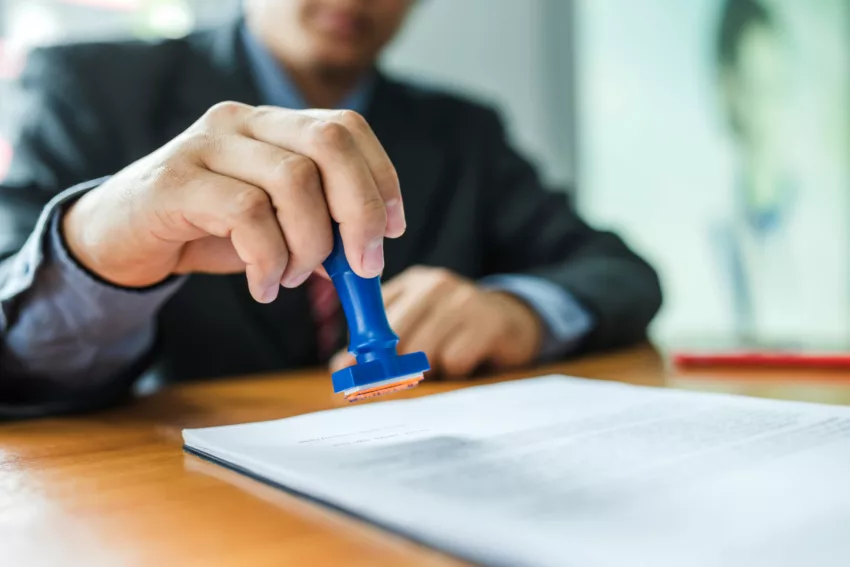 Businessman Stamping With Approved Stamp On Document At Meeting.