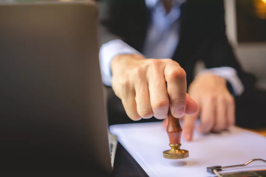 Close Up Of A Person's Hand Stamping With Approved Stamp On Approval Certificate Document Public Paper At Desk, Notary Or Business People Work From Home, Isolated For Coronavirus COVID 19 Protection