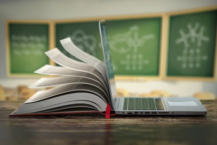 E Learning Online Education Or Internet Encyclopedia Concept. Open Laptop And Book Compilation In A Classroom.